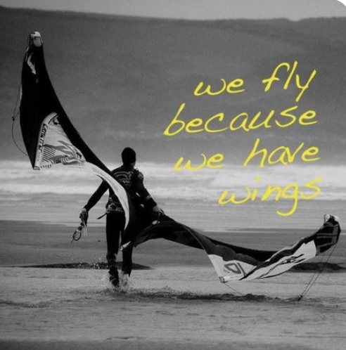 Black-and-white image of a kiter walking out of the surf