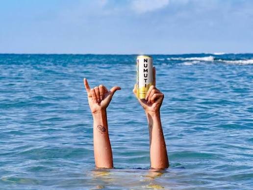 Hands rising out of the sea holding a NuMuti can
