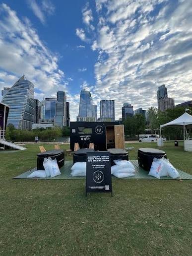 Cold plunge tubs and a sauna on a mat on grass